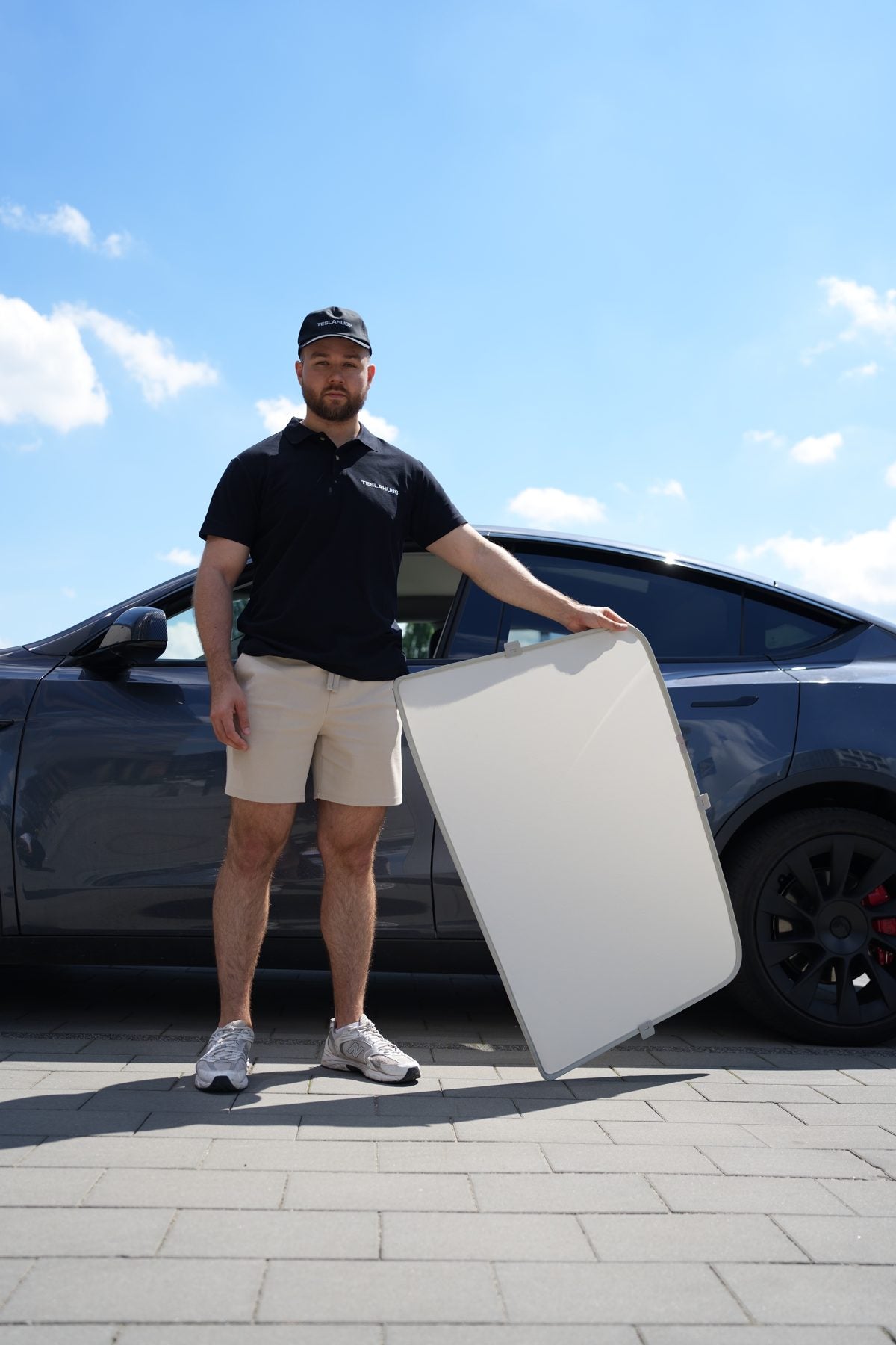 TeslaHubs team member with a Solar Shield roof sunshade next to a Tesla